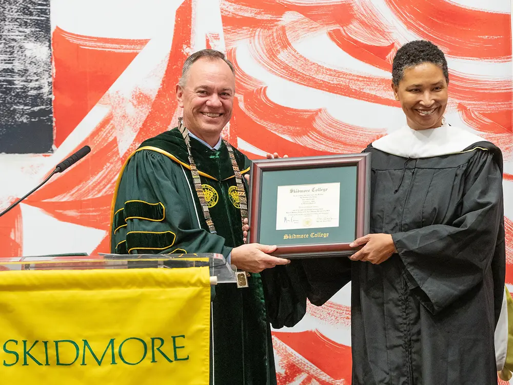 Danielle Allen receives a degree from Marc Conner in front of a red and white U.S. flag design. 