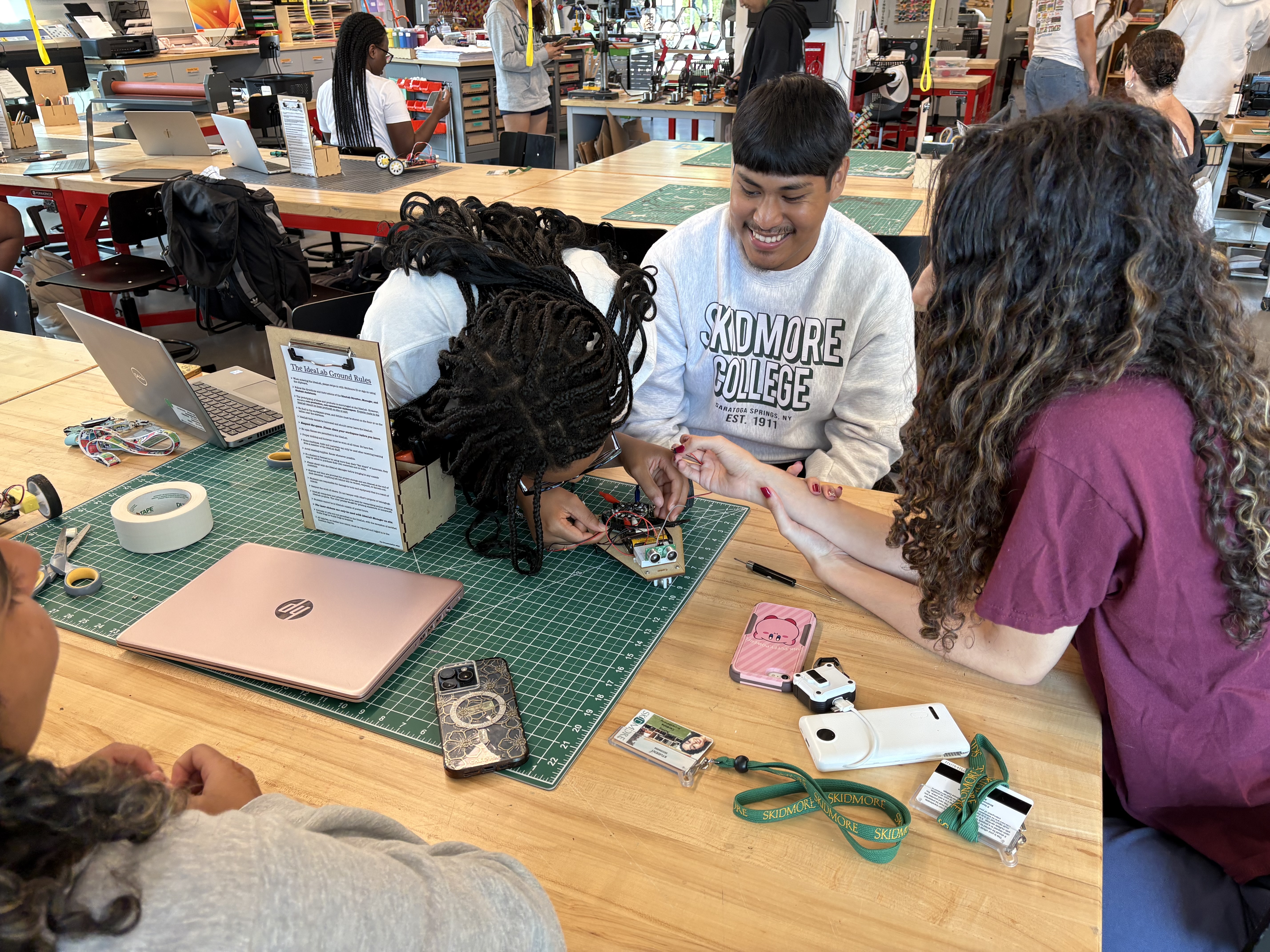 Students in a Skidmore College makerspace work together on a small robotics project, surrounded by tools and laptops.