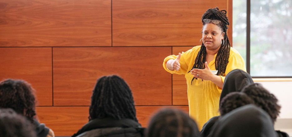 Kelli Rouse stands in front of a group of seated students.
