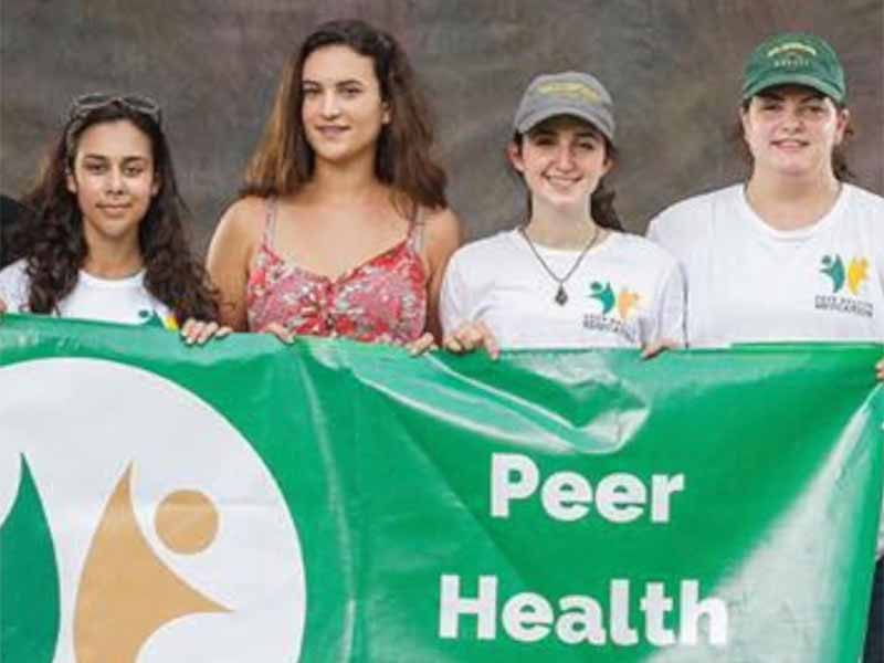 4 students holding a banner that says Peer Health Educators