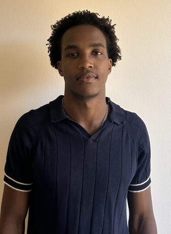 Student staff smiling wearing navy blue polo shirt against white wall