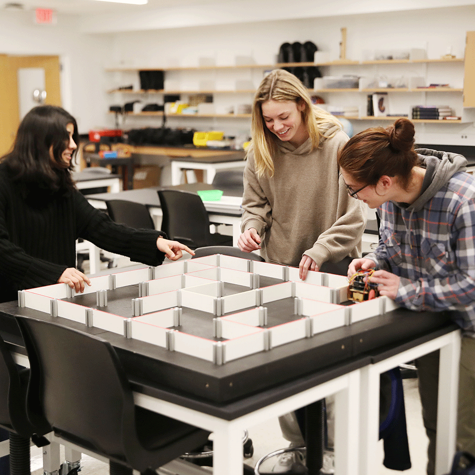 Three students work on maze in a physics lab