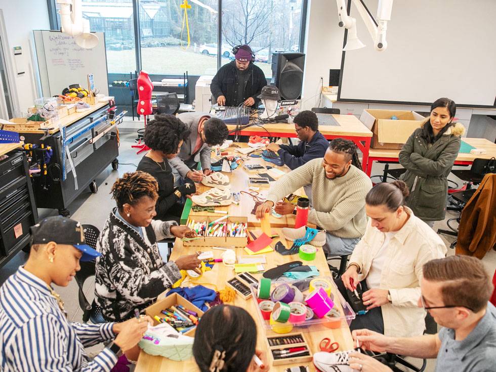A group of people work at a colorful table in the Schupf Family Idea Lab