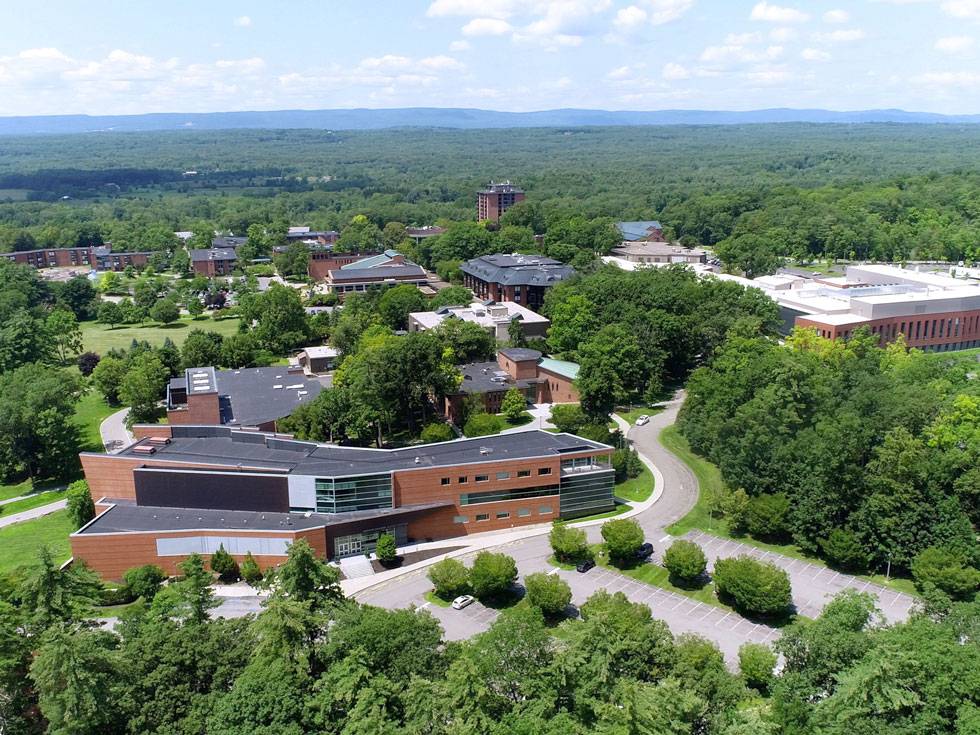 An aerial view of Skidmore's campus on a beautiful blue sky day, with green mountains in the background.