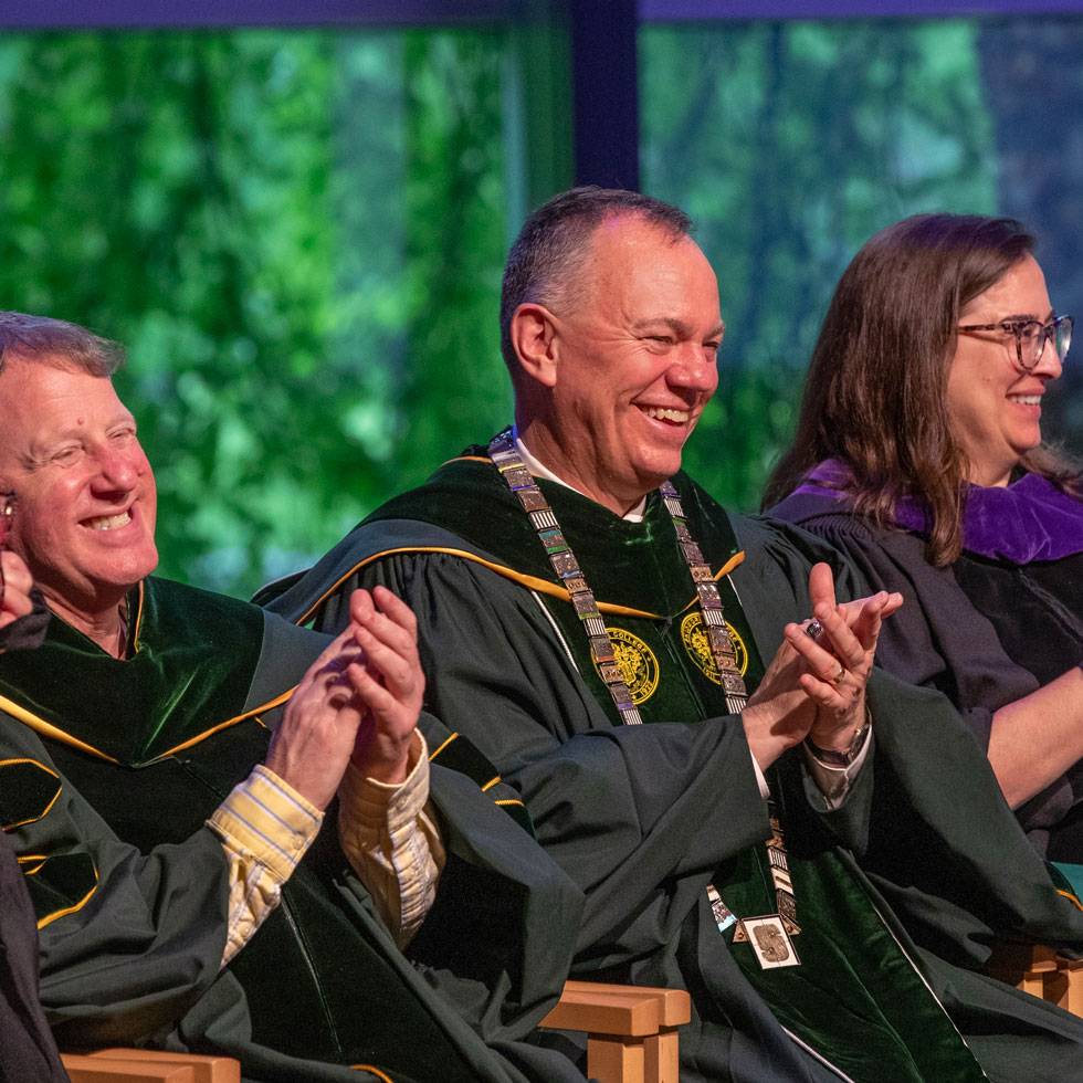 Presidents Conner on stage with alumni board members at the reunion alumni awards ceremony. They are all wearing matching Skidmore regalia.