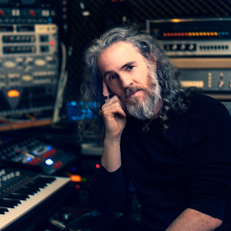 Scott Jacoby sits in a recording studio with his head leaning gently on his right hand.