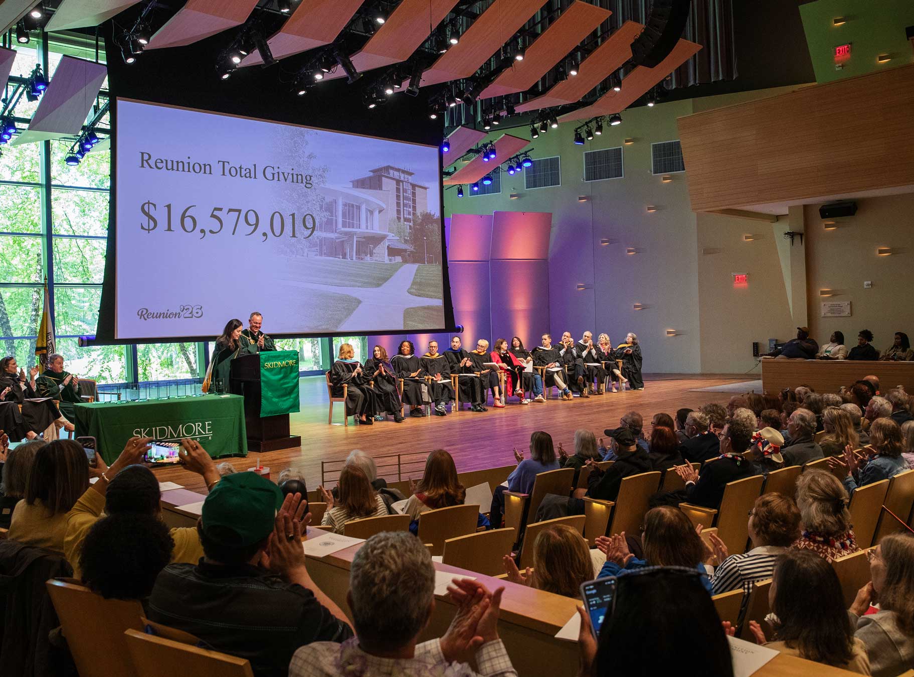 A Skidmore College Reunion ceremony shows a projected Reunion giving total of $16,579,019 as attendees applaud.