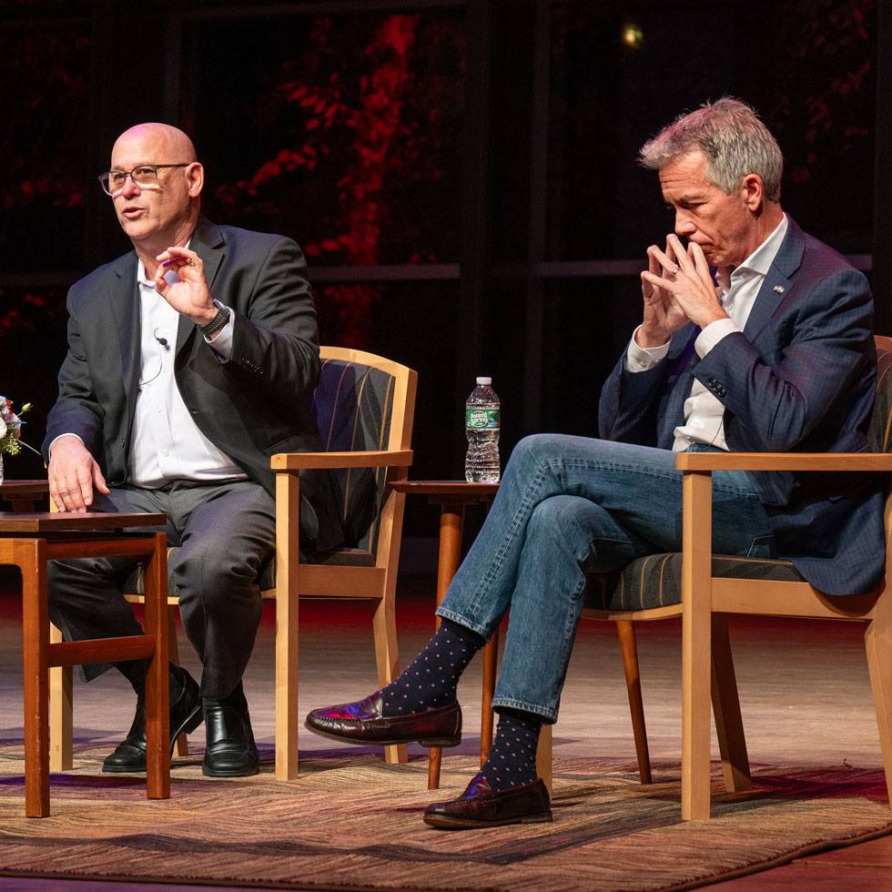 Fred Guttenberg '88 sits on stage presenting in a large auditorium with a presenting partner sitting next to him.