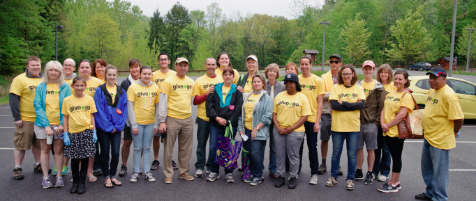 team of volunteers wearing bright yellow shirts line up in parking lot before the event