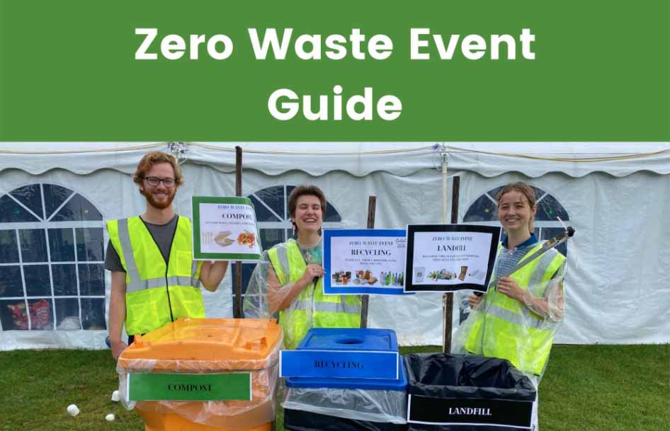 People stand with trash grabbers smiling by waste bins at an event.