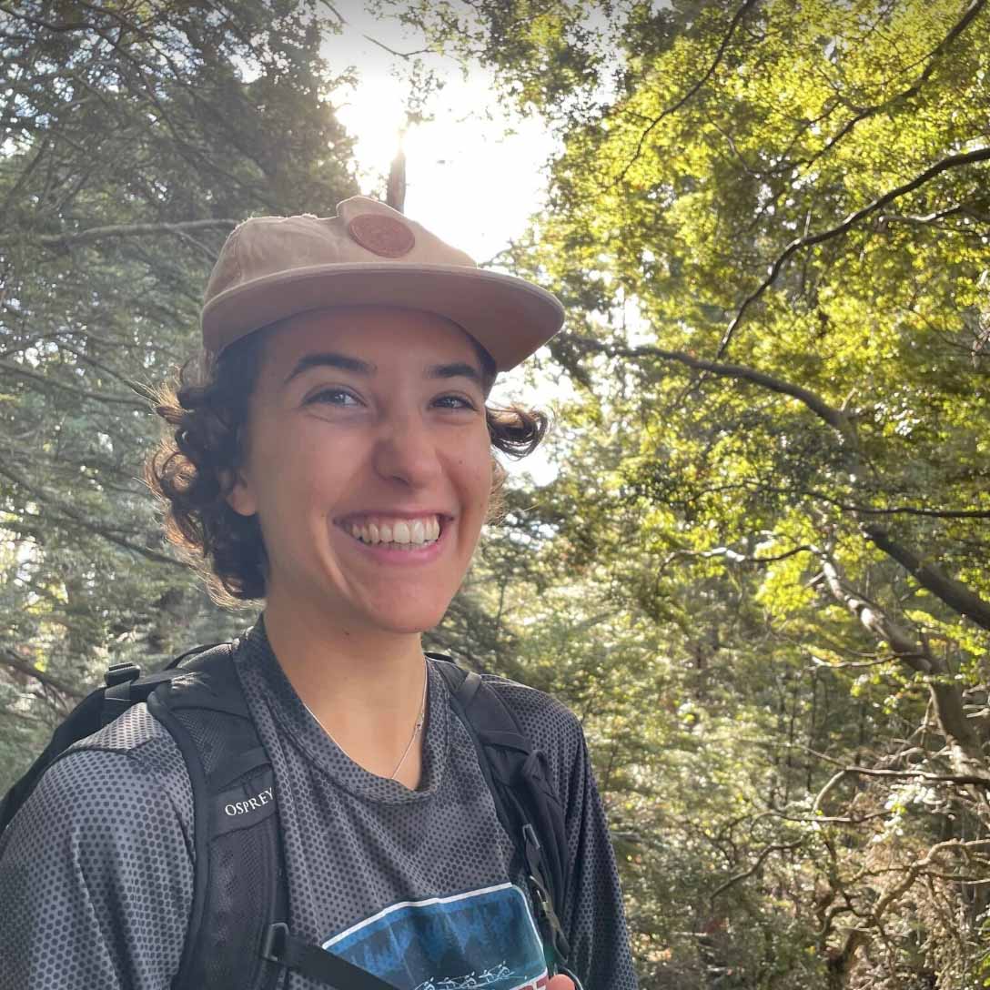 Isabella smiles before a background of lush forest