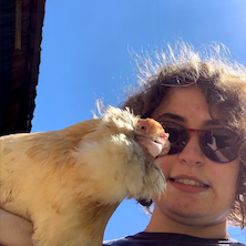 Maggie smiles with a chicken in her arm