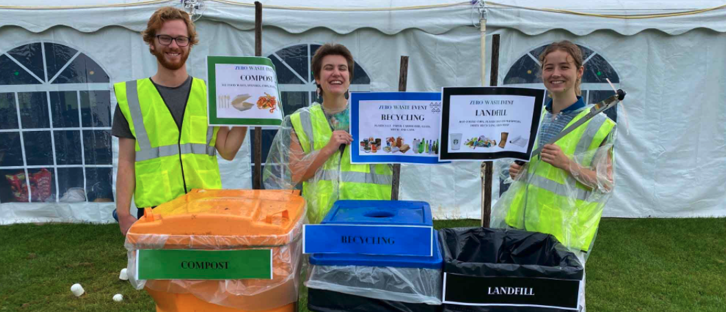 three smiling student staff with waste bins at an event