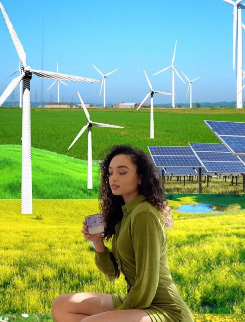 Summer Dean kneeling with a cup of tea with wind mills, solar panels, and fields in the background