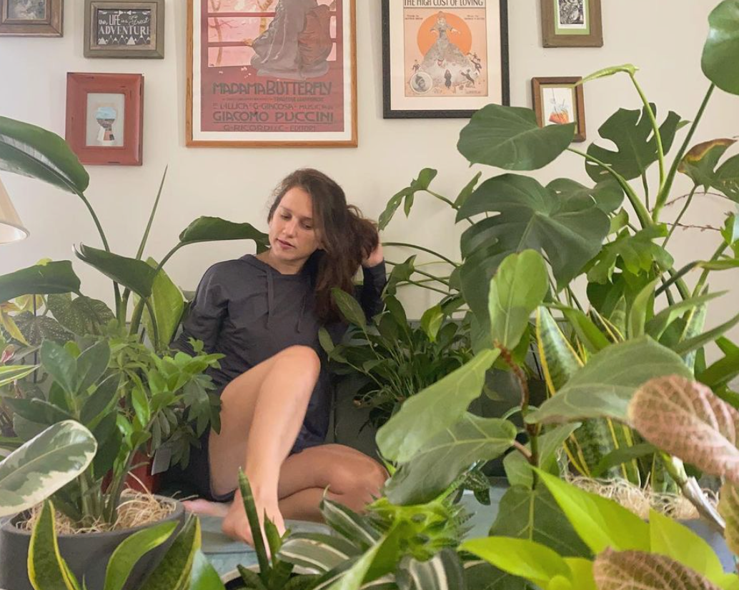 Photo of Femislay on a couch surrounded by plants