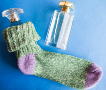one glass perfume bottle is tucked inside a cotton sock. A second perfume bottle sits next to the pair.