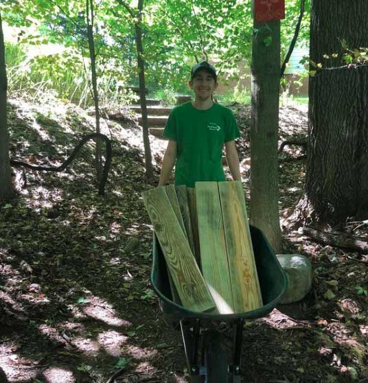 Jacob Adams '21 holds wheelbarrow filled with lumber