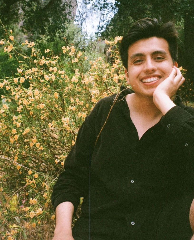 Isaias Hernandez posing in front of flowers