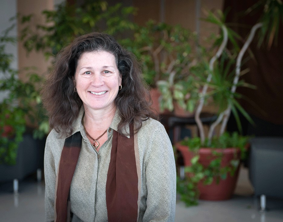 Professor Diana Barnes poses with plants in the background