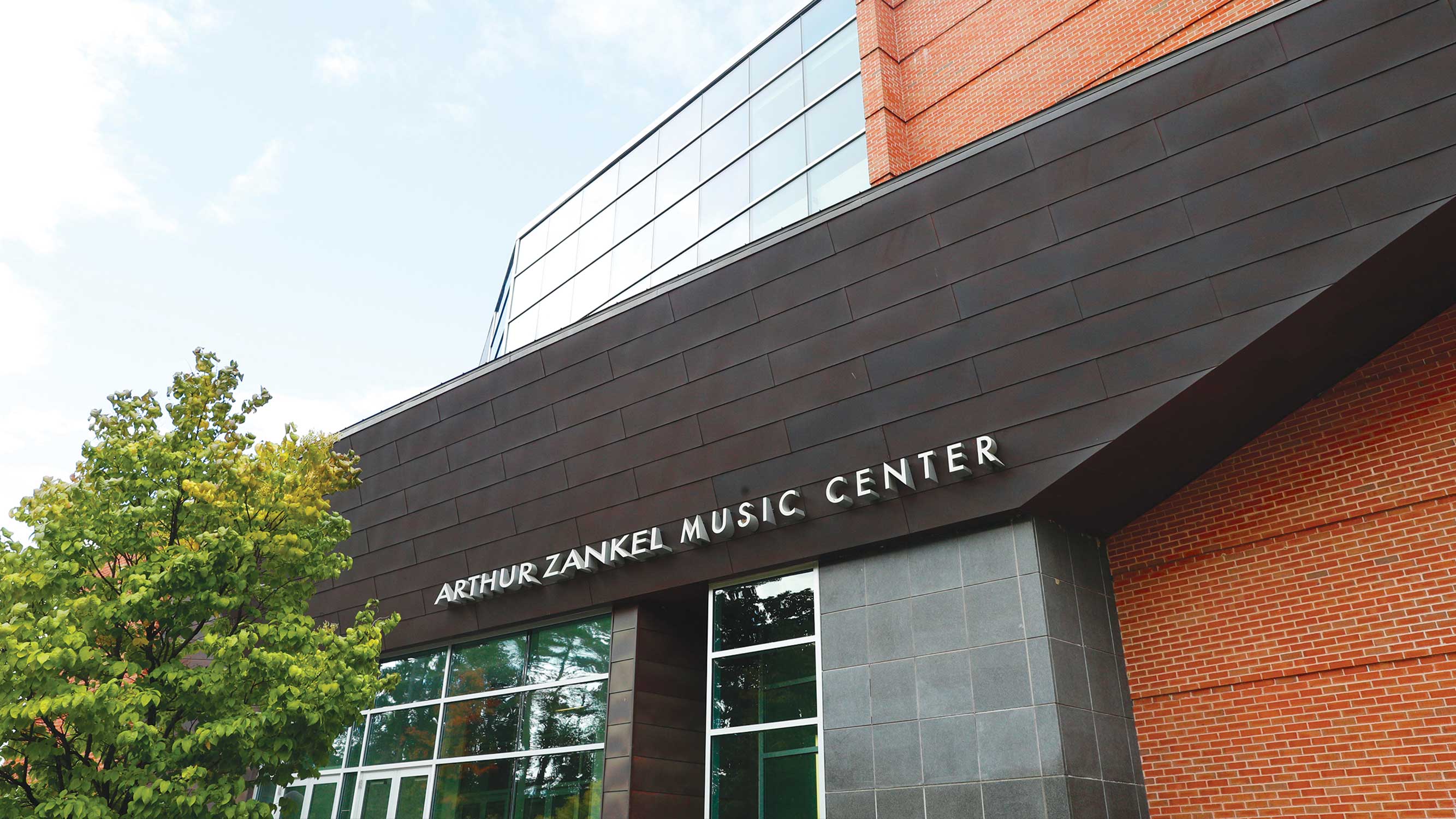 Exterior of Skidmore’s Arthur Zankel Music Center, showing the building’s glass entrance, brick facade, and signage.